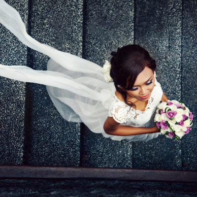 Woman in wedding dress holding a flower bouquet walking down the stairs